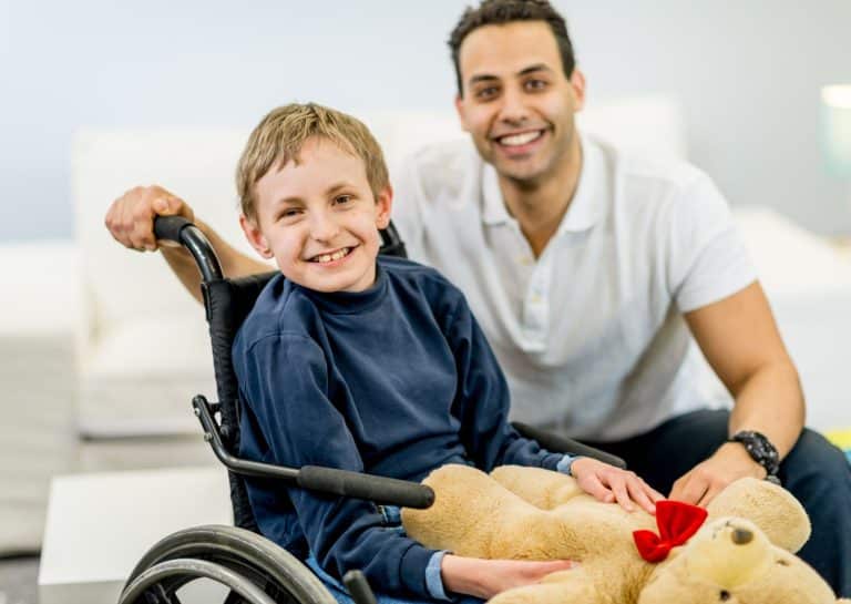 Enfant en fauteuil roulant jouant avec adulte et peluche